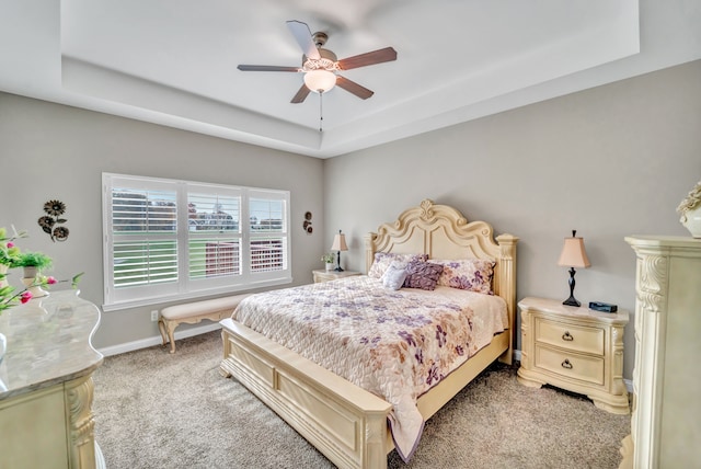 carpeted bedroom featuring a tray ceiling and ceiling fan