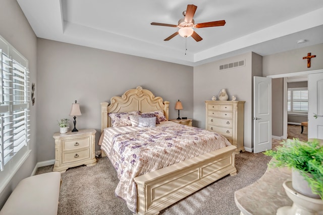 carpeted bedroom featuring ceiling fan and a raised ceiling