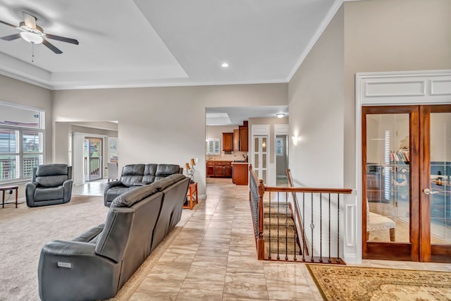 living room with french doors, a tray ceiling, light colored carpet, ceiling fan, and crown molding