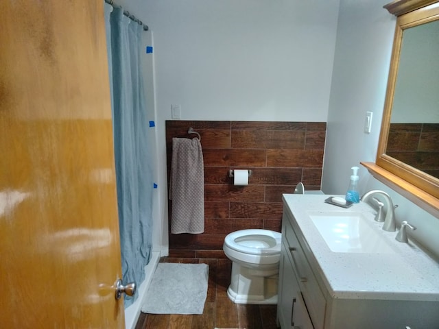 bathroom with wood walls, wood-type flooring, toilet, vanity, and a shower with shower curtain