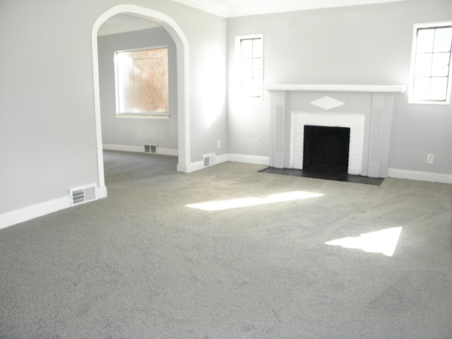 unfurnished living room featuring carpet flooring, crown molding, and a brick fireplace