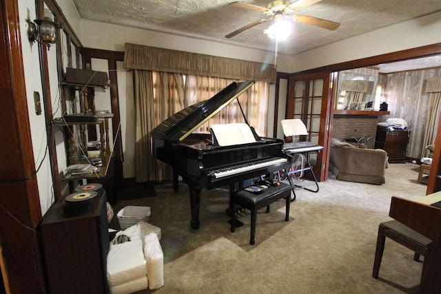 misc room featuring a textured ceiling, light colored carpet, a brick fireplace, and ceiling fan