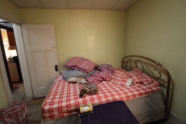 bedroom with a paneled ceiling and hardwood / wood-style floors