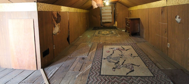 corridor with hardwood / wood-style floors, vaulted ceiling, and wood walls