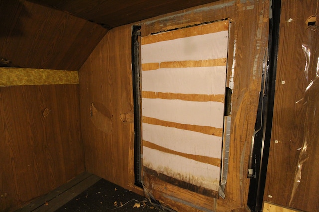 additional living space with wood walls and lofted ceiling