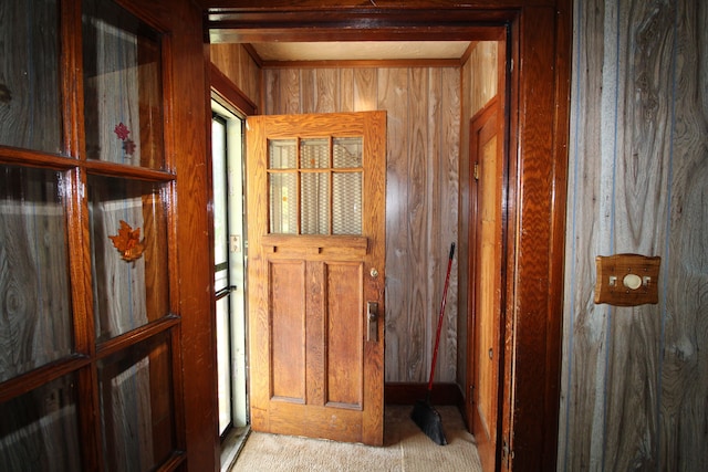 hallway featuring wooden walls and light colored carpet