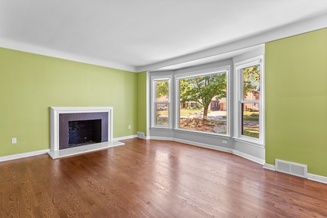 unfurnished living room featuring hardwood / wood-style floors and a tiled fireplace