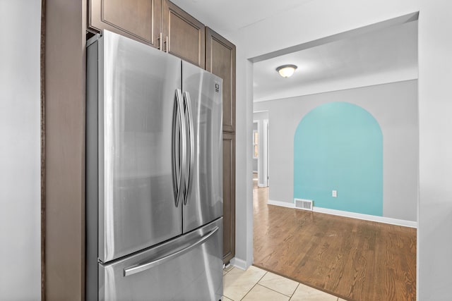 kitchen with stainless steel fridge, dark brown cabinetry, and light hardwood / wood-style flooring