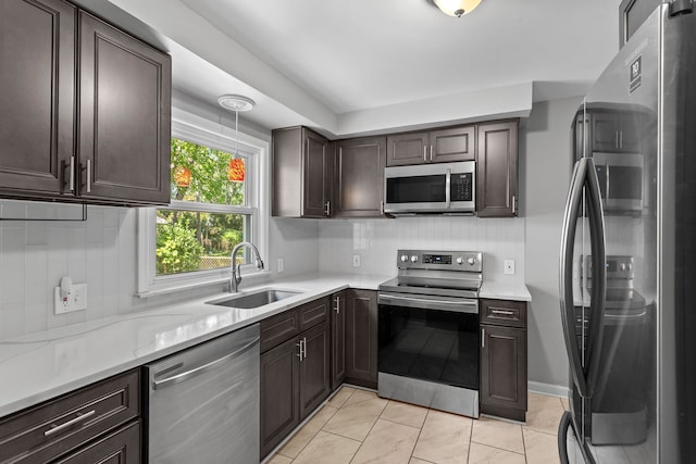 kitchen featuring decorative backsplash, appliances with stainless steel finishes, light stone counters, dark brown cabinetry, and sink