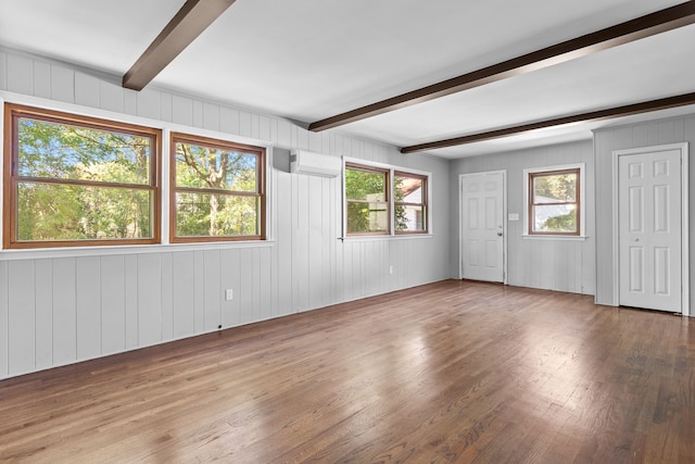 empty room featuring beam ceiling, a wall mounted AC, wooden walls, and hardwood / wood-style floors