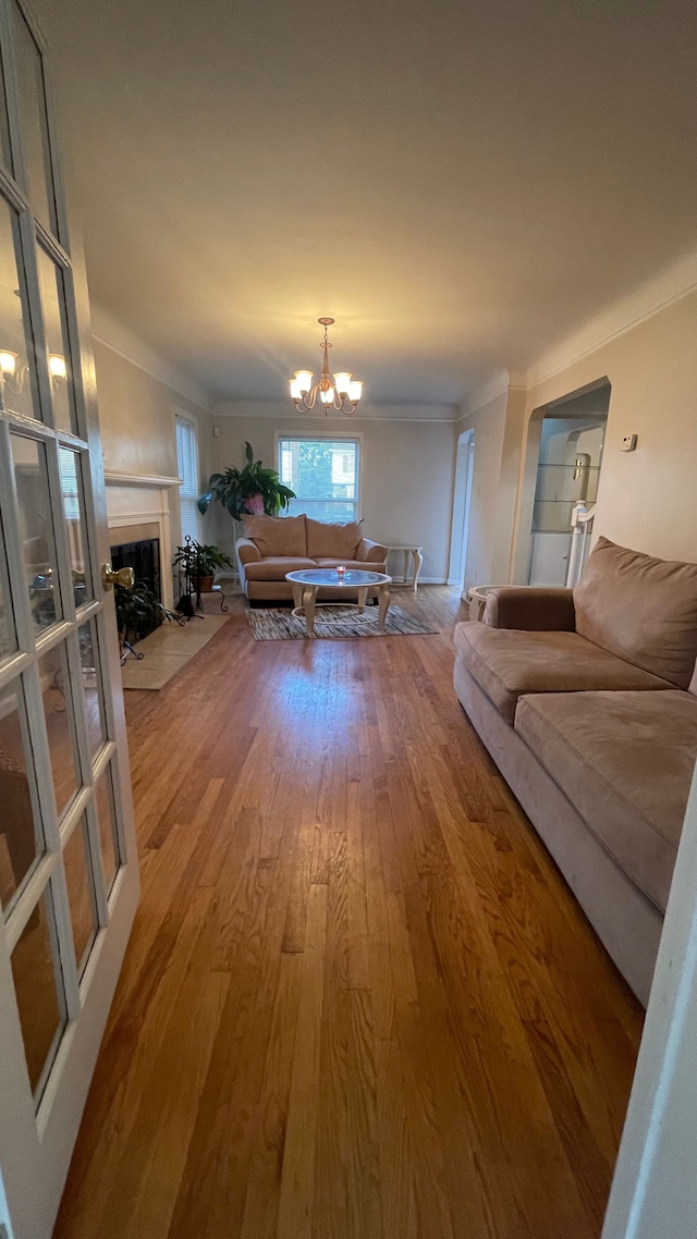 unfurnished living room with crown molding, wood-type flooring, and an inviting chandelier