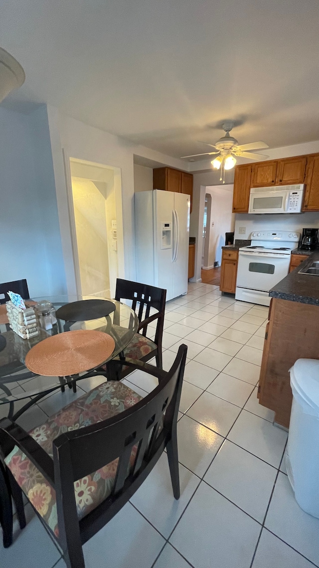 tiled dining room with ceiling fan and sink