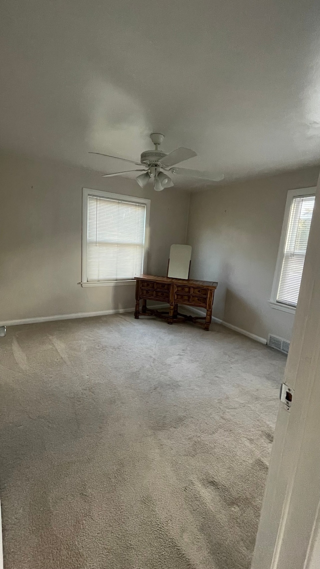 carpeted empty room featuring a wealth of natural light and ceiling fan