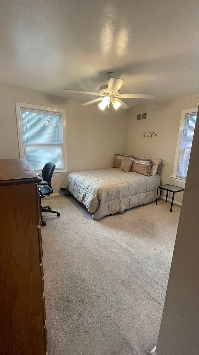 carpeted bedroom with multiple windows and ceiling fan