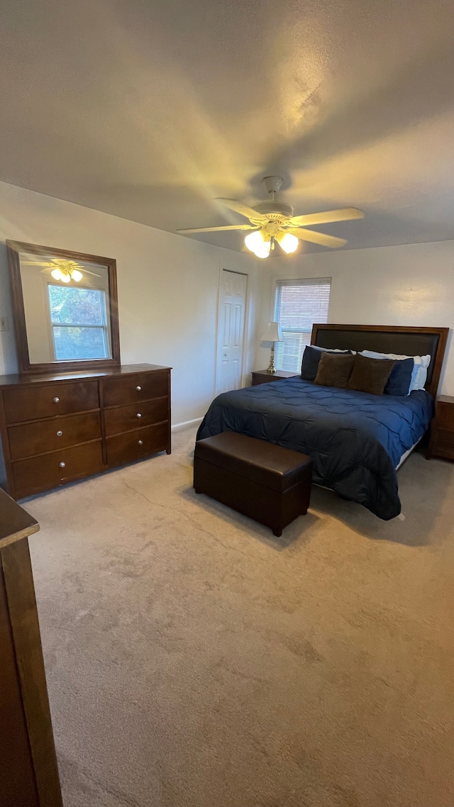 carpeted bedroom featuring ceiling fan and a closet