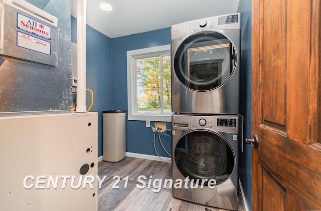 laundry room with hardwood / wood-style flooring, stacked washing maching and dryer, and heating unit