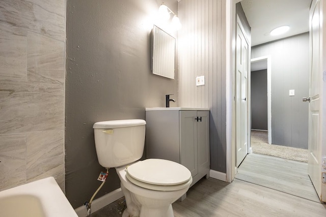 bathroom with a tub to relax in, vanity, hardwood / wood-style flooring, and toilet