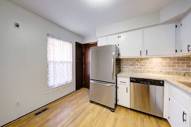 kitchen featuring stainless steel appliances, light wood-style flooring, visible vents, and tasteful backsplash