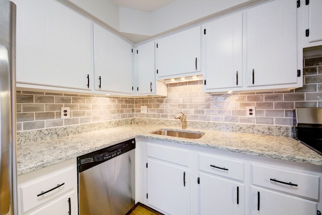 kitchen with light stone countertops, white cabinetry, sink, stainless steel appliances, and tasteful backsplash