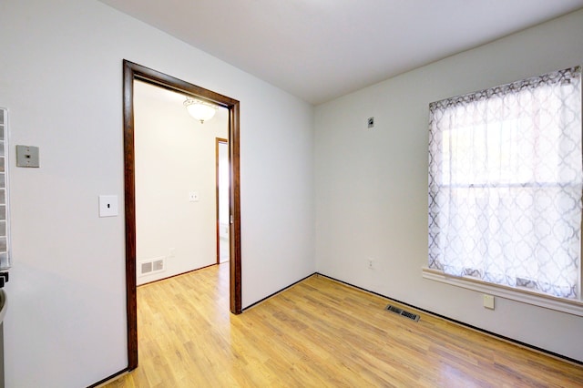 unfurnished room featuring light wood-style flooring, visible vents, and a wealth of natural light