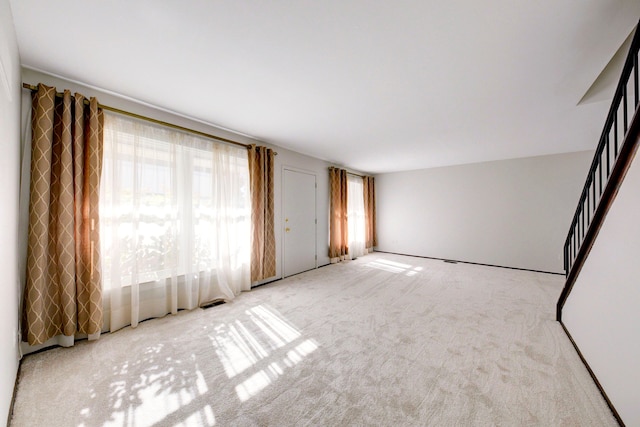 carpeted empty room with visible vents and stairs
