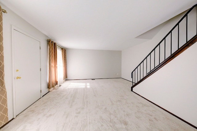 unfurnished living room with carpet and stairway