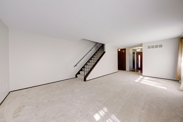 unfurnished living room with carpet flooring, visible vents, and stairway