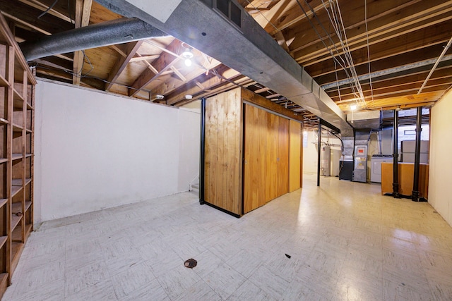 unfinished basement with visible vents, tile patterned floors, and water heater