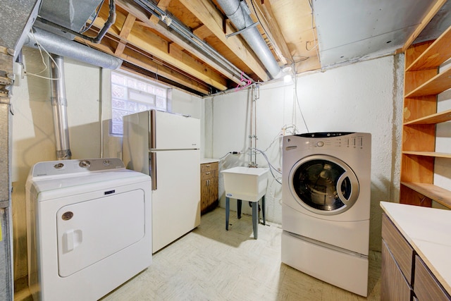 laundry area featuring washer and clothes dryer, cabinets, and sink