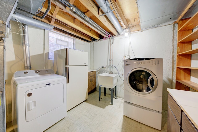 laundry room with light floors, a sink, independent washer and dryer, and cabinet space