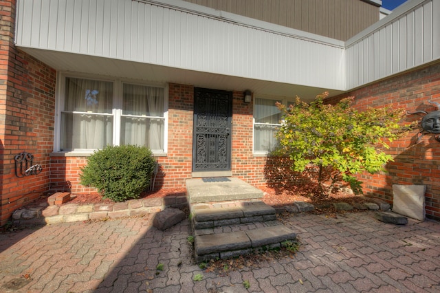 doorway to property featuring brick siding and a porch