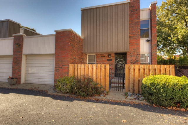 contemporary house with a gate, a fenced front yard, a chimney, a garage, and brick siding