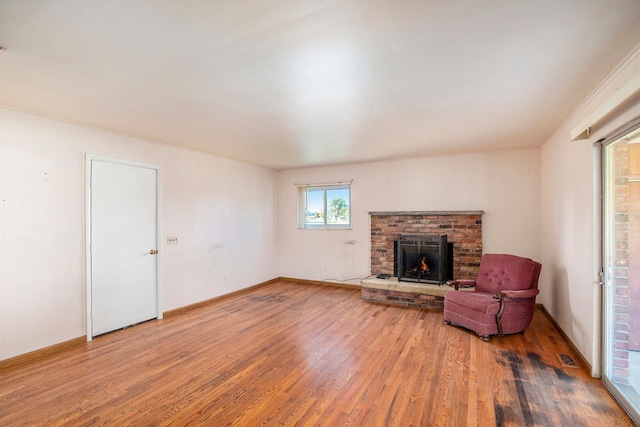 unfurnished living room featuring hardwood / wood-style flooring, a brick fireplace, and crown molding