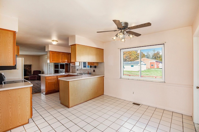 kitchen with ceiling fan, a brick fireplace, kitchen peninsula, white appliances, and light tile patterned floors