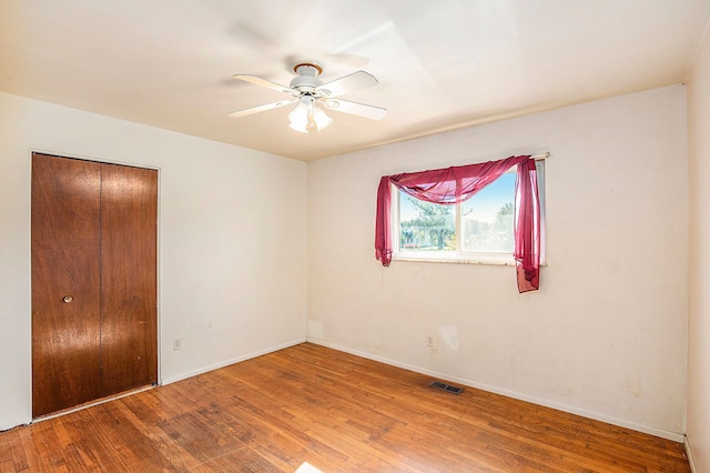 unfurnished bedroom featuring hardwood / wood-style floors, ceiling fan, and a closet