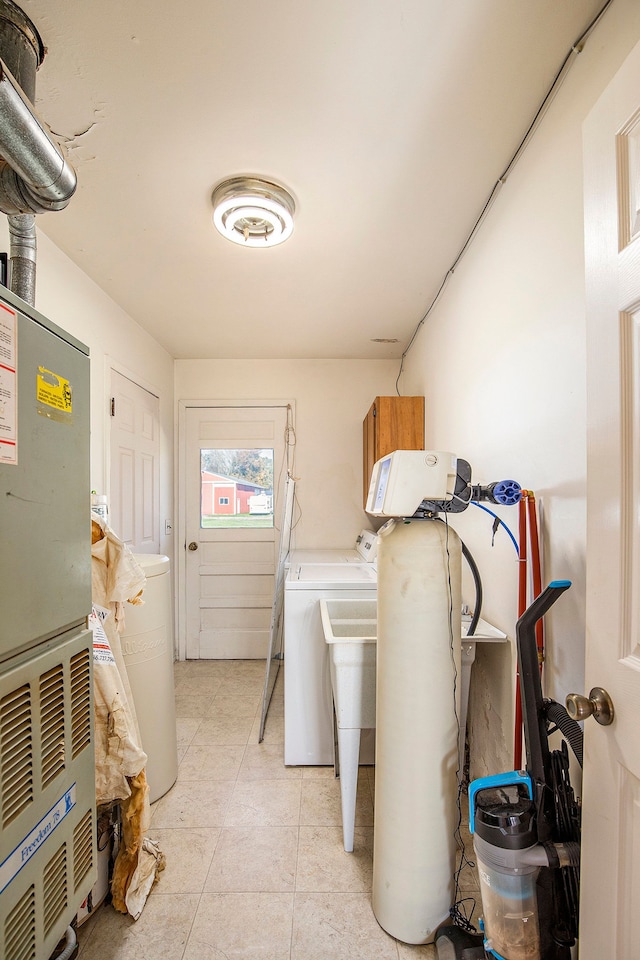 laundry room featuring washing machine and clothes dryer, heating unit, light tile patterned floors, and cabinets