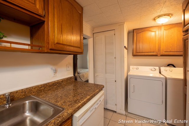 laundry area with washer and clothes dryer, light tile patterned floors, cabinets, and sink