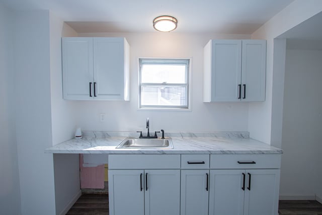 kitchen with dark hardwood / wood-style flooring, white cabinetry, and sink