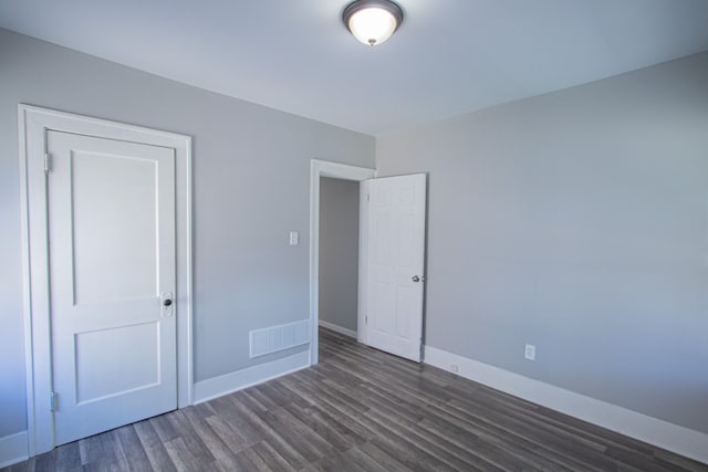 unfurnished bedroom with dark hardwood / wood-style flooring and a closet