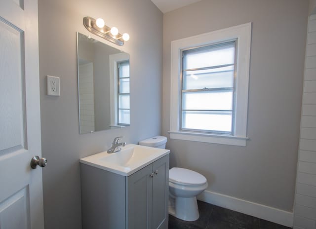 bathroom featuring tile patterned floors, vanity, a healthy amount of sunlight, and toilet