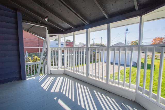 unfurnished sunroom with plenty of natural light and lofted ceiling with beams