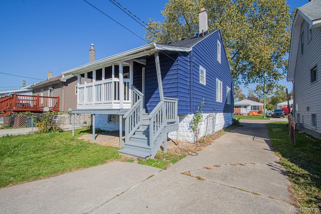 23930 Elmira St, Saint Clair Shores, MI 48082 - view of front of home featuring a chimney, a front lawn, concrete driveway, and a deck