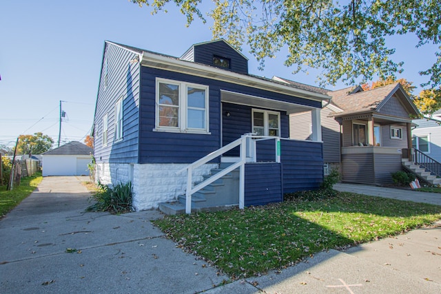 bungalow with a garage, an outdoor structure, and a front lawn