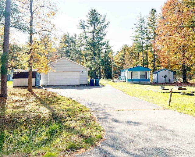 exterior space featuring a lawn, a garage, and a storage unit