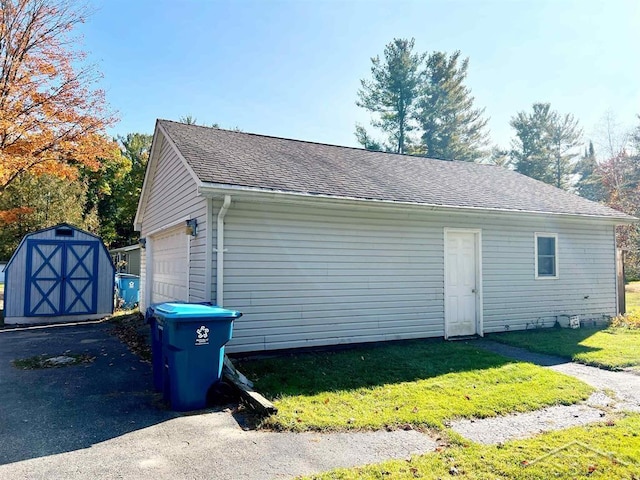 view of property exterior with a lawn, a garage, and a storage shed