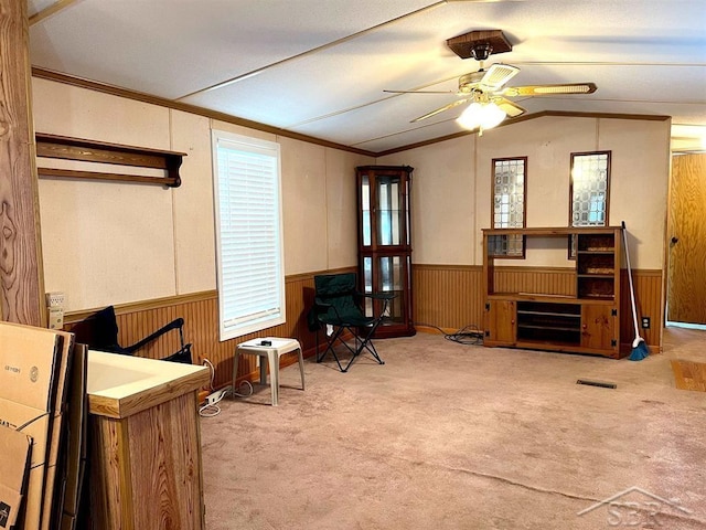 living area with light colored carpet, a wealth of natural light, lofted ceiling, and wood walls