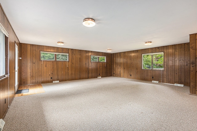 unfurnished room with carpet flooring and wood walls