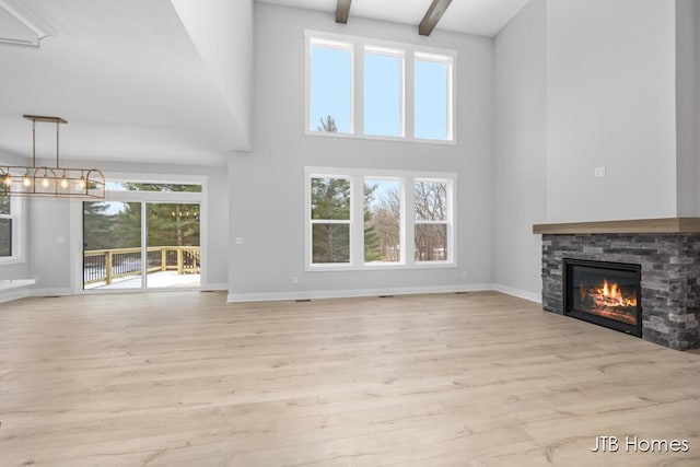 unfurnished living room with a fireplace, baseboards, wood finished floors, and beamed ceiling