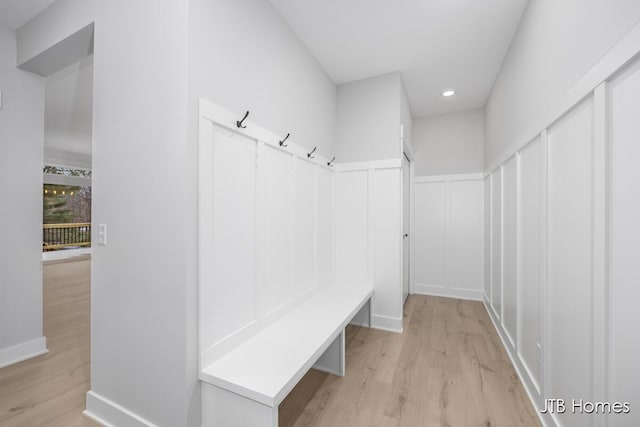 mudroom with light wood-style floors, recessed lighting, a decorative wall, and wainscoting