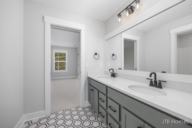 full bath with double vanity, a sink, and baseboards